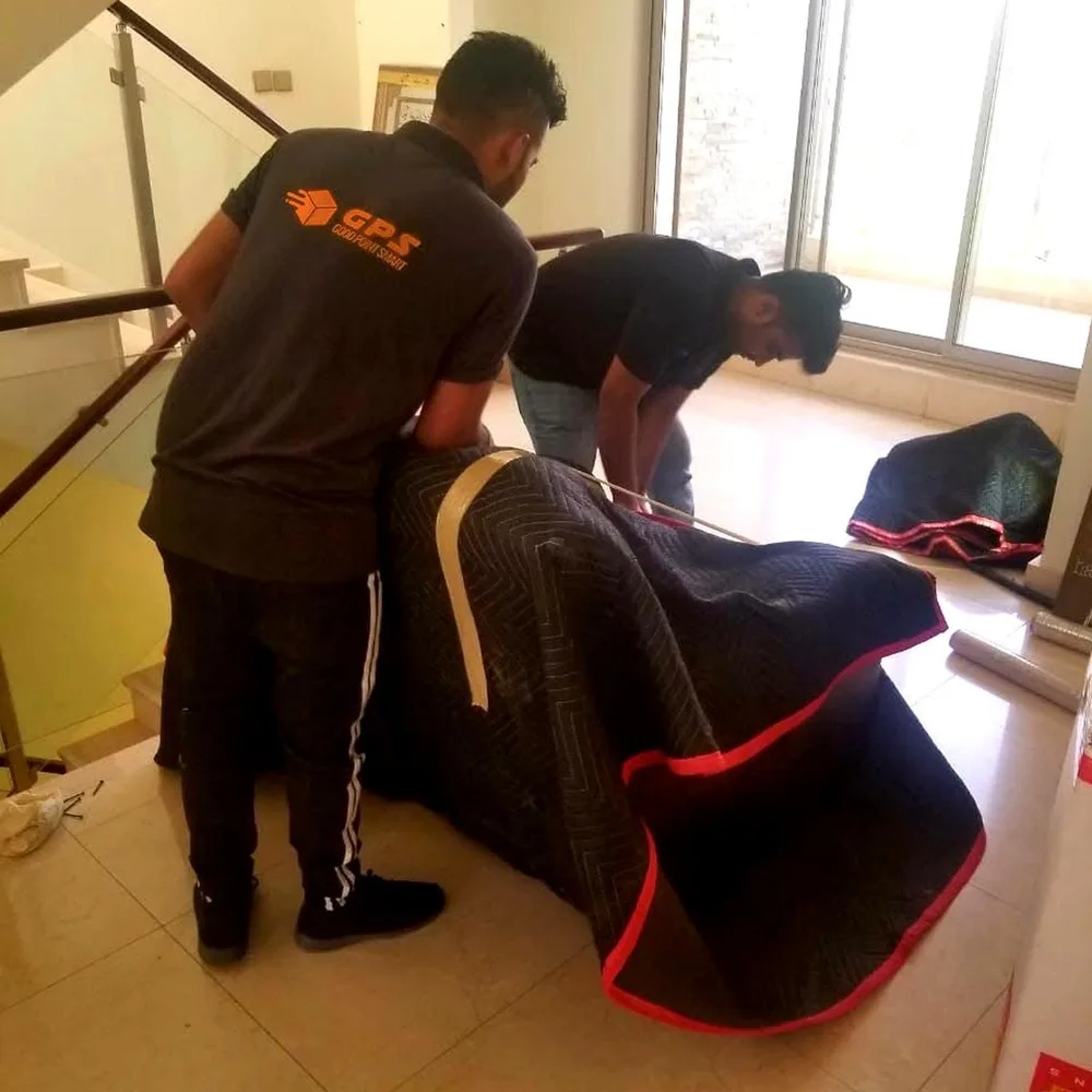 GPS Movers crew wrapping furniture in quilted moving blankets inside a Dubai villa