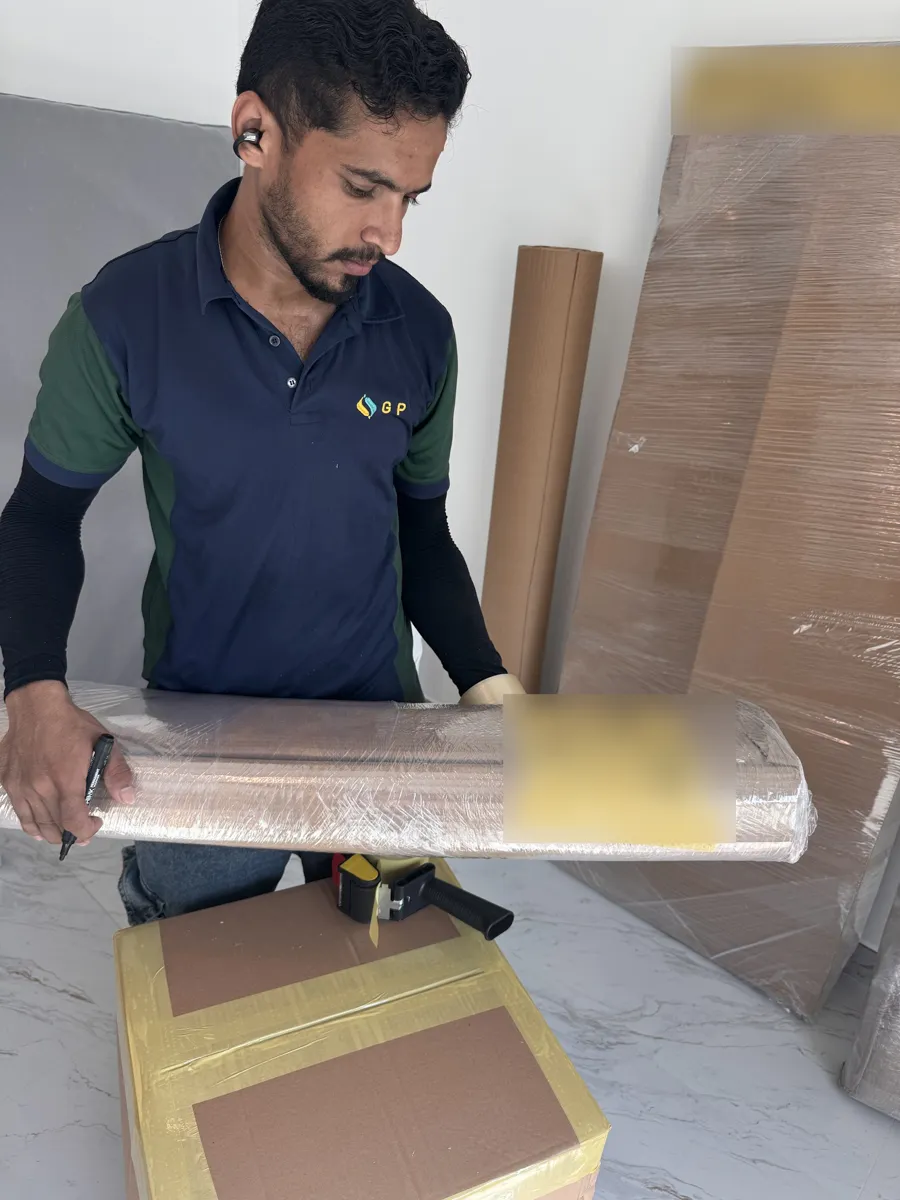 GPS Movers crew member labelling a wrapped bed frame with its room before a premium move