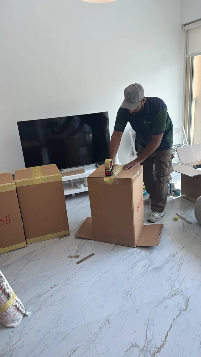 GPS Movers crew member sealing moving boxes with a tape gun