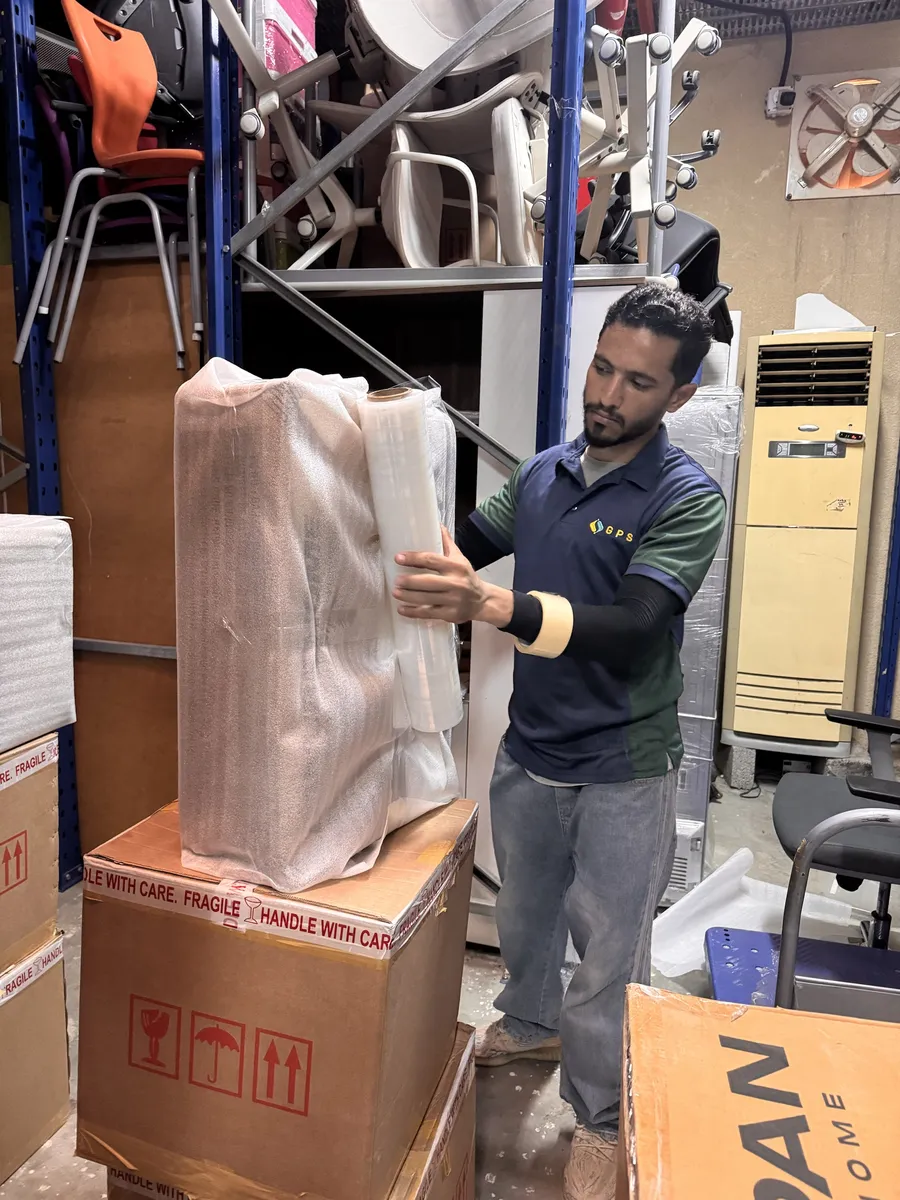 GPS Movers crew member wrapping furniture for storage
