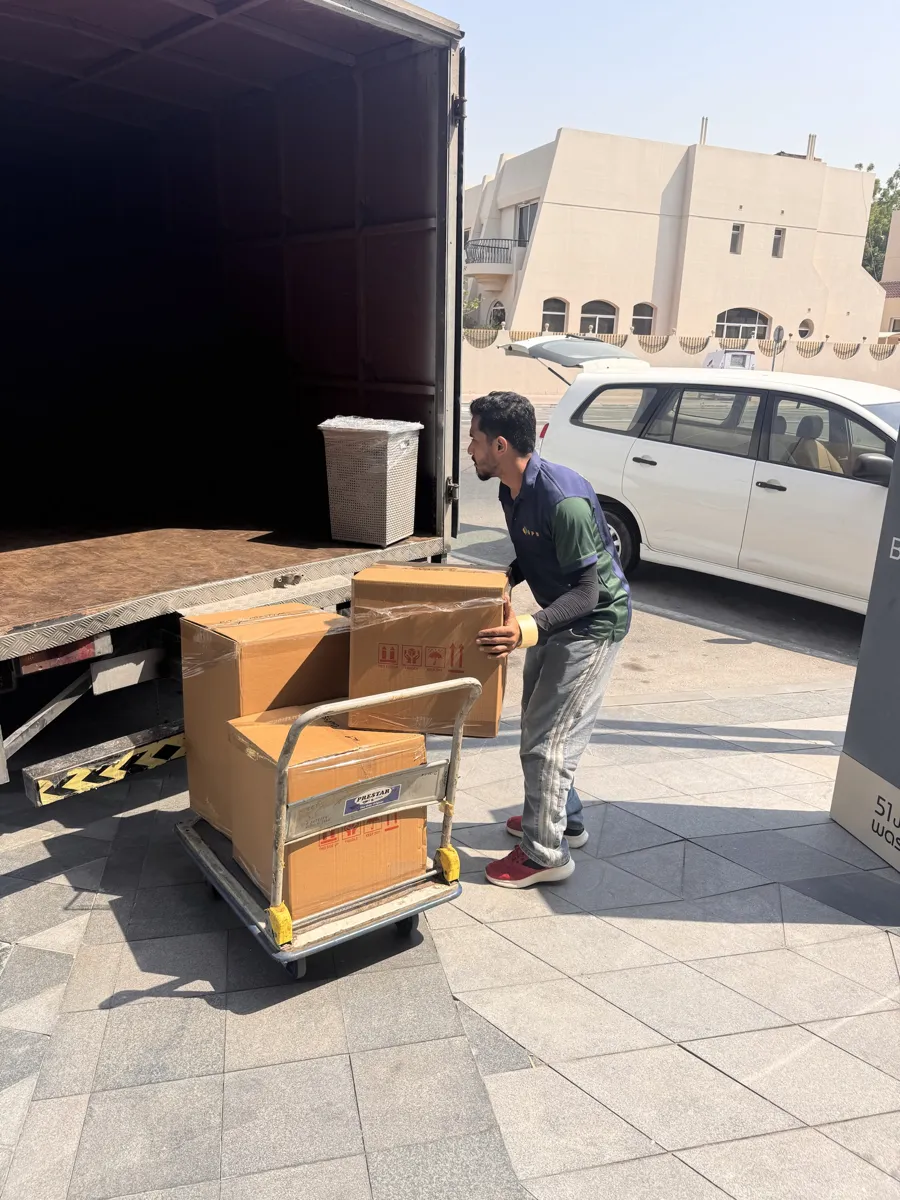 GPS Movers crew loading packed boxes into a closed box truck outside a Dubai villa